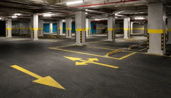Well-designed basement car parking interior with lighting, ventilation, directional signs and safety markings.